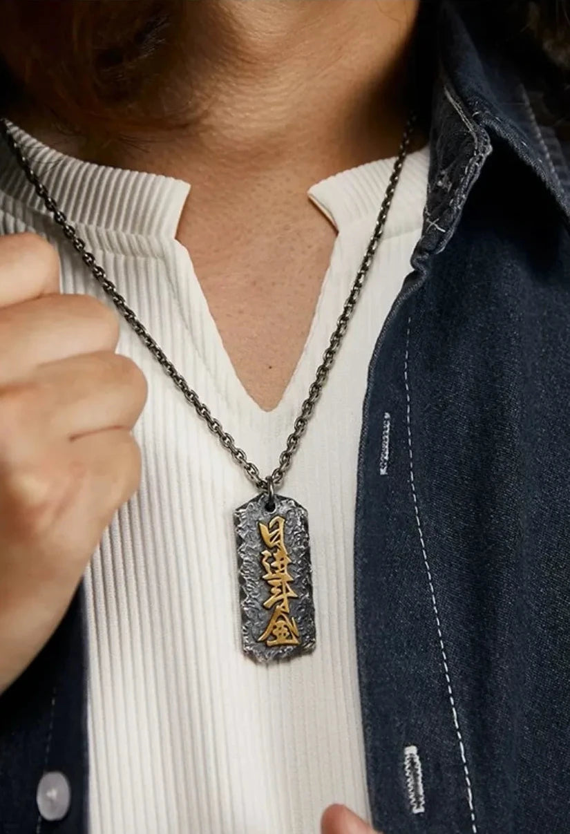 Man wearing a rustic oxidized silver dog tag pendant with gold Chinese characters "Ri Jin Dou Jin" (Daily Wealth), styled with a denim shirt