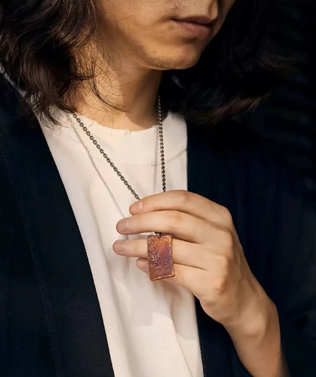Model holding the auspicious cloud pendant, highlighting the rufous and bluing color details against a white shirt