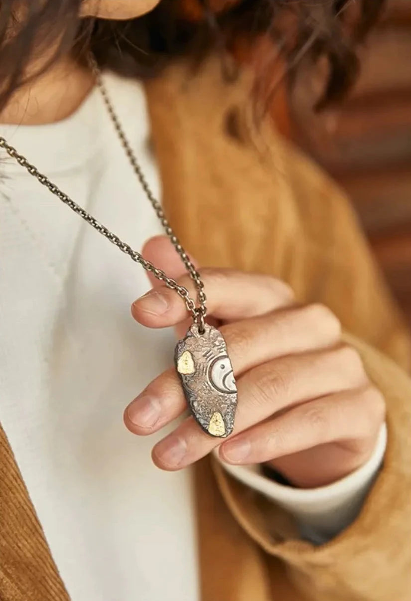 Close-up of a model holding the Bagua necklace, emphasizing the intricate bluing and gold craftsmanship