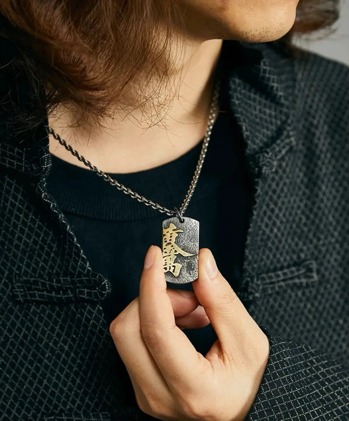 Detailed view of the Fortune pendant in a model's hand, emphasizing the craftsmanship and Chinese calligraphy