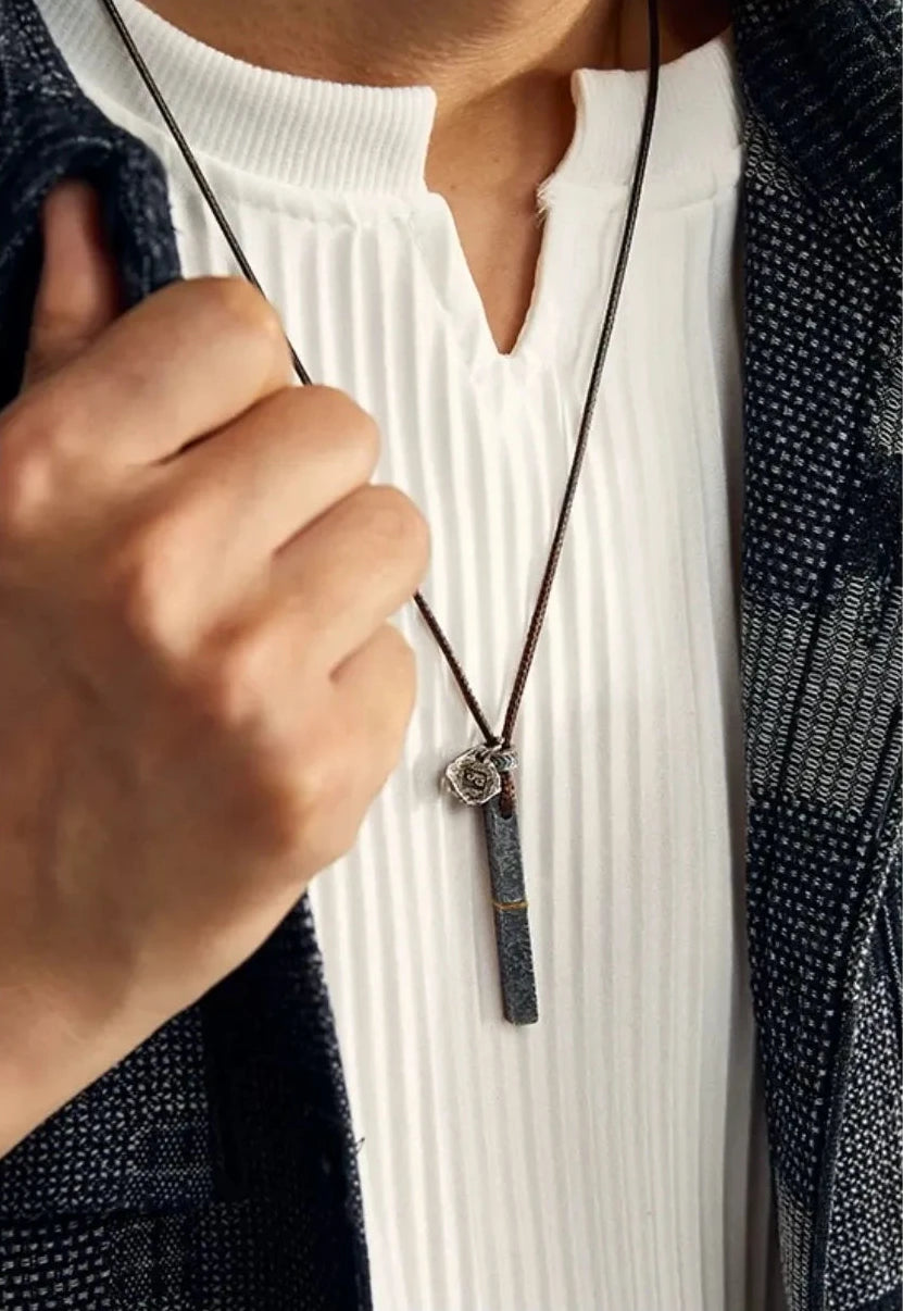 Close-up of a model holding the Prosperous necklace, emphasizing the contrast between silver and gold details
