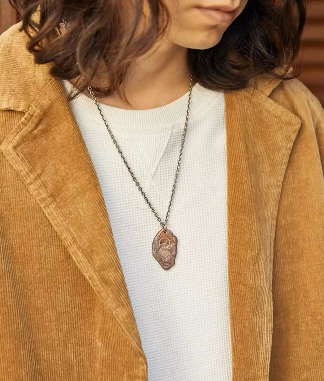 Model wearing the Celestial Stag necklace, styled with a brown corduroy jacket