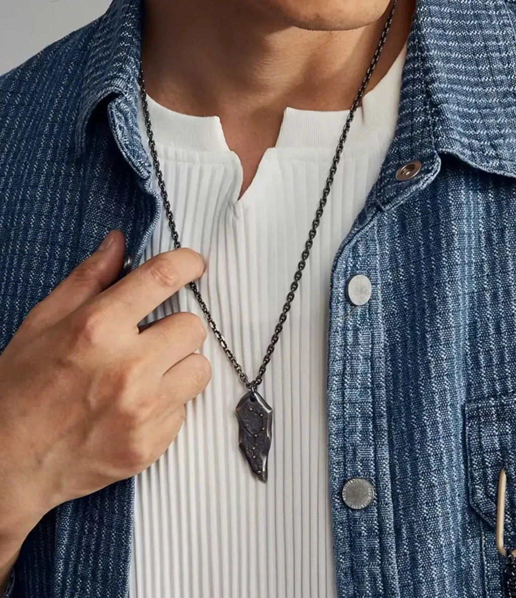 Close-up of the model touching the pendant, highlighting the contrast between the dark silver and gold star accents