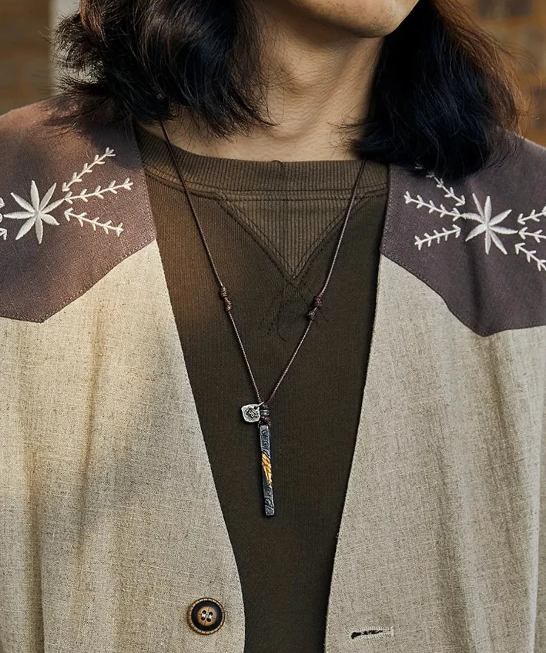 Model wearing the vital flame pendant styled with an earth-tone embroidered jacket