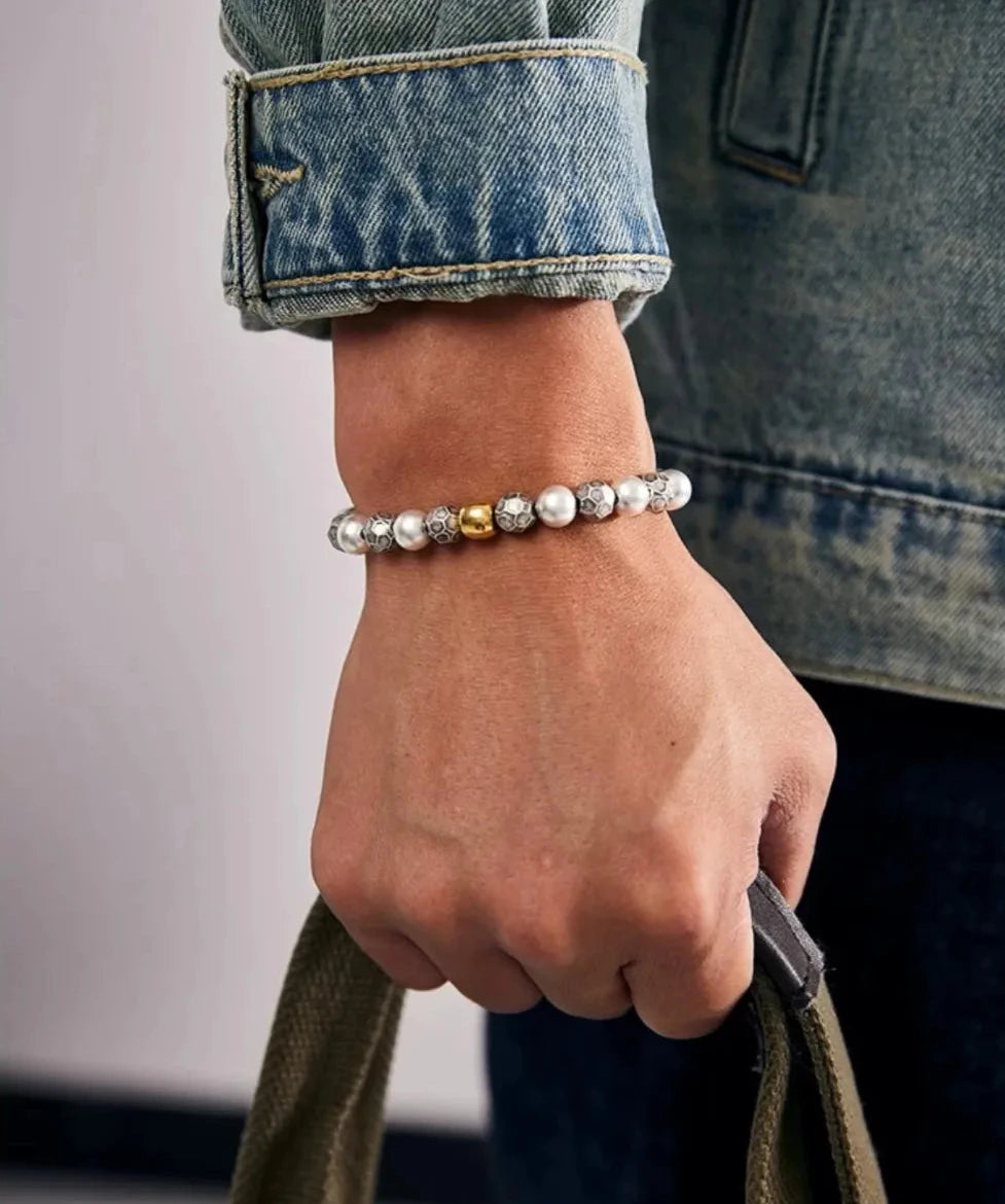 Lifestyle shot of a man holding a bag, showcasing how the pearl and silver bracelet complements a rugged denim jacket