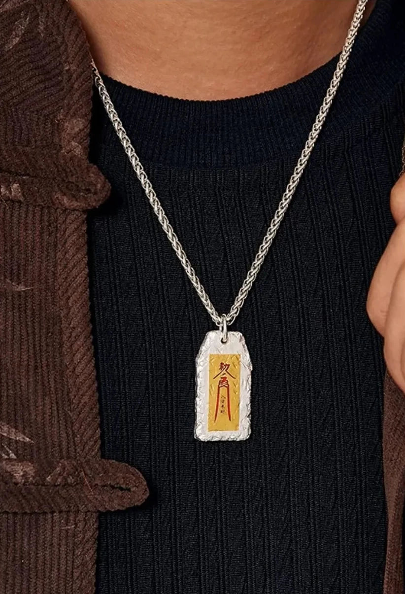 A man wearing the Taoism talisman necklace styled with a traditional brown tang suit jacket