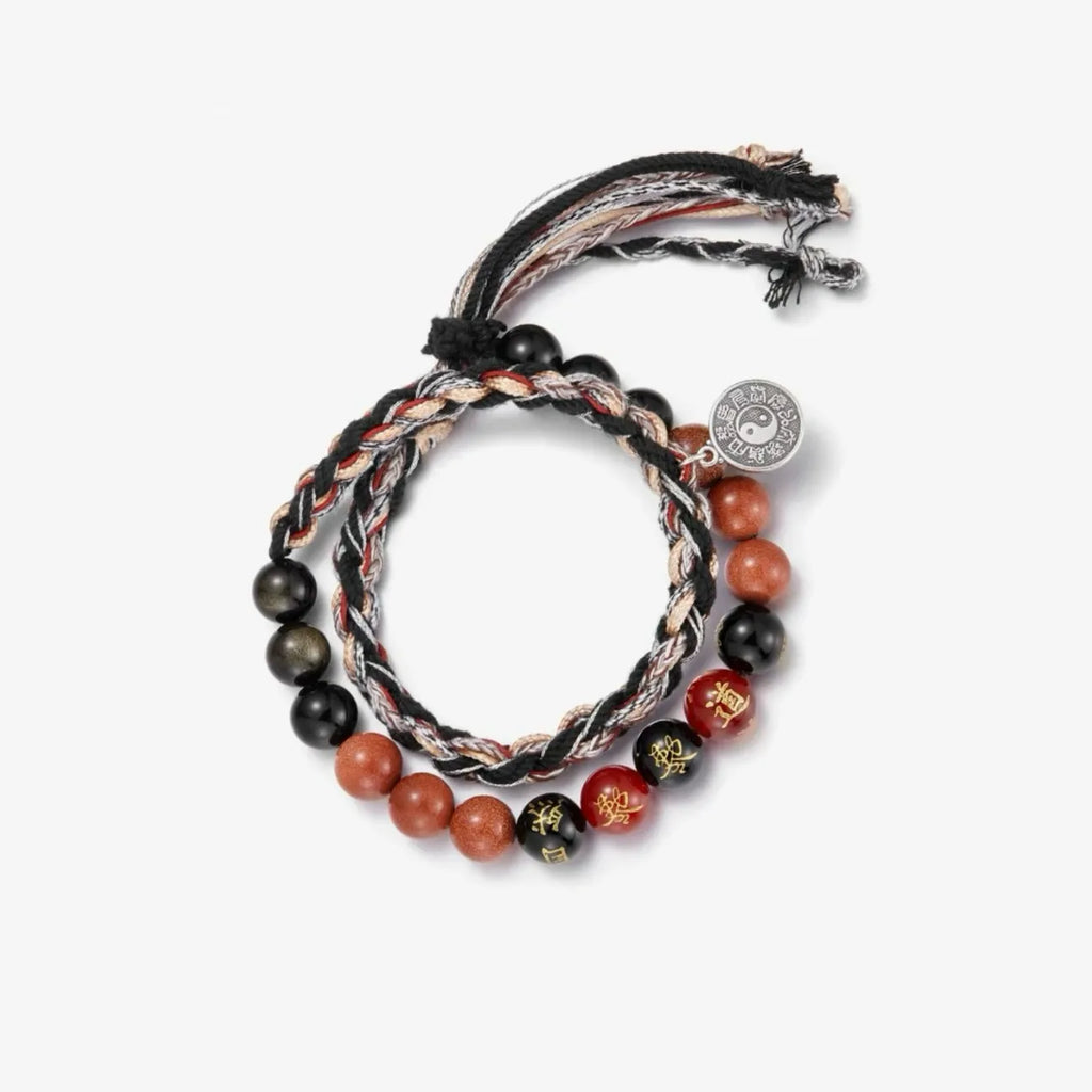 Top-down macro shot capturing the golden sparkles in the red stones and the gold calligraphy on the black onyx beads