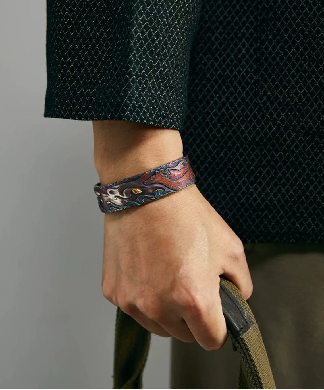 Model in a dark waffle-knit jacket adjusting his collar, showcasing the divine deer bangle as a statement accessory