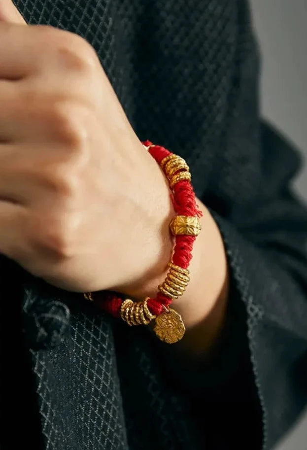 Close-up on the wrist featuring the dangling gold coin charm, symbolizing wealth and prosperity