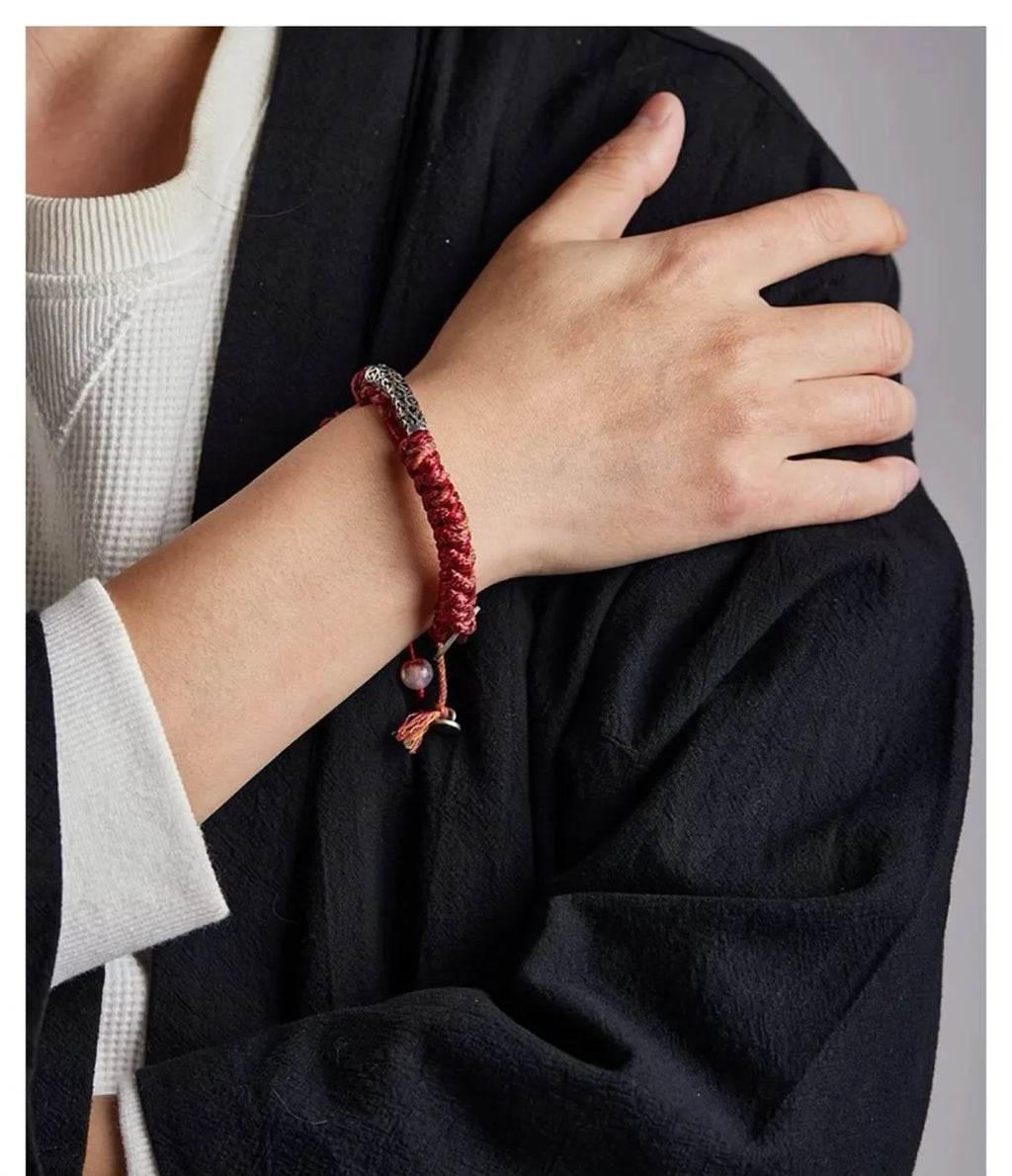 Detailed wrist shot focusing on the silver tube and the vibrant red texture of the woven cotton cord