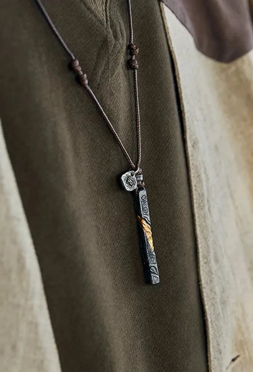 Front chest view of the twisted bar necklace worn over a brown shirt and ethnic vest
