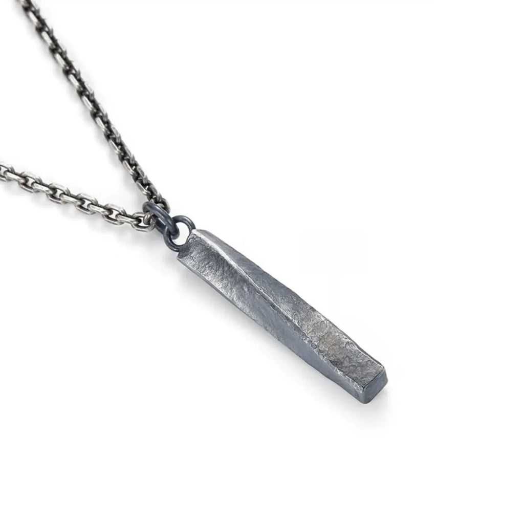 Angled shot showing the geometric twist of the silver bar and the rugged texture of the metal