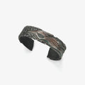 Front view of a dark oxidized silver bangle featuring a relief sculpture of a Red-crowned Crane flying amidst clouds
