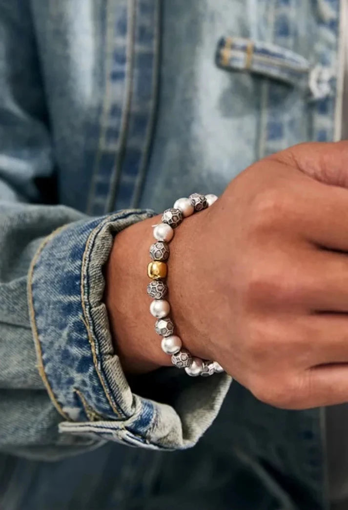 Close-up on the wrist showing the texture contrast between the matte "Formless" metal beads and the lustrous pearls