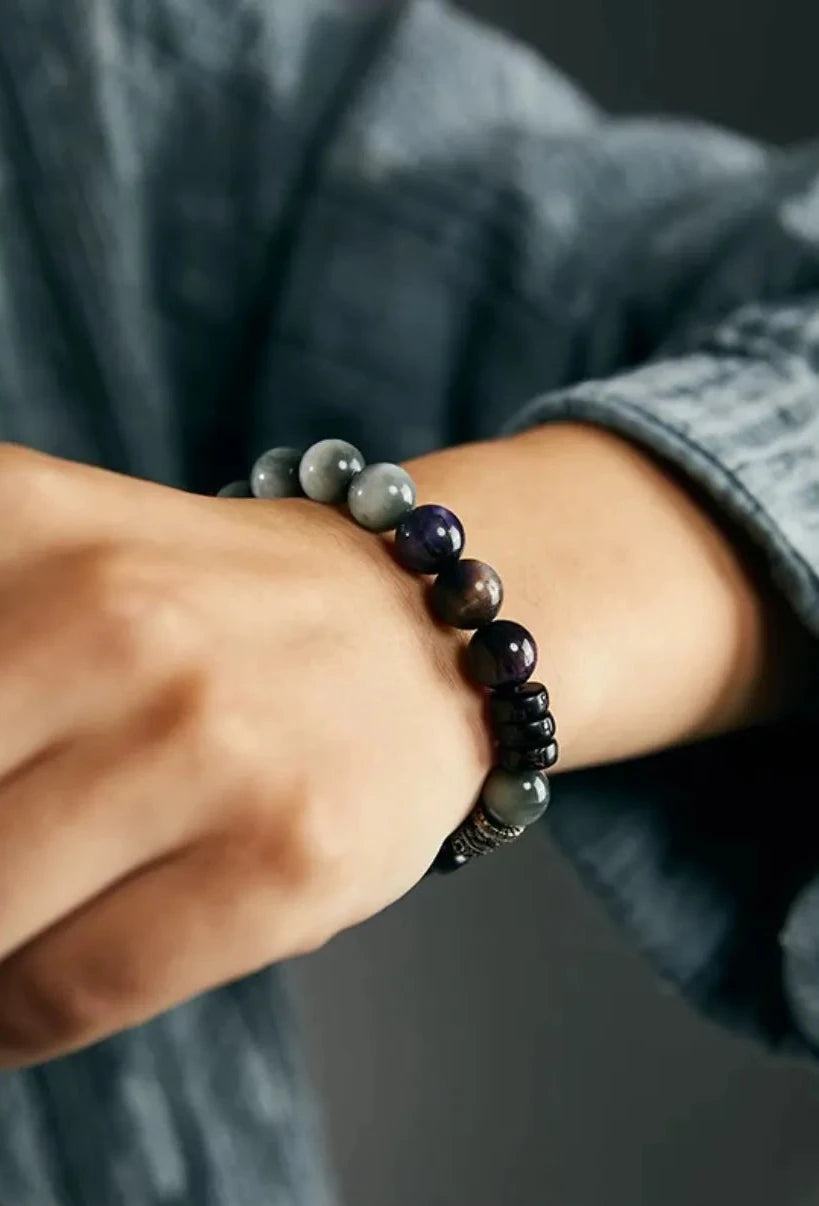 Close-up on the wrist displaying the silky chatoyancy of the purple tiger eye and grey eagle eye stones under natural light