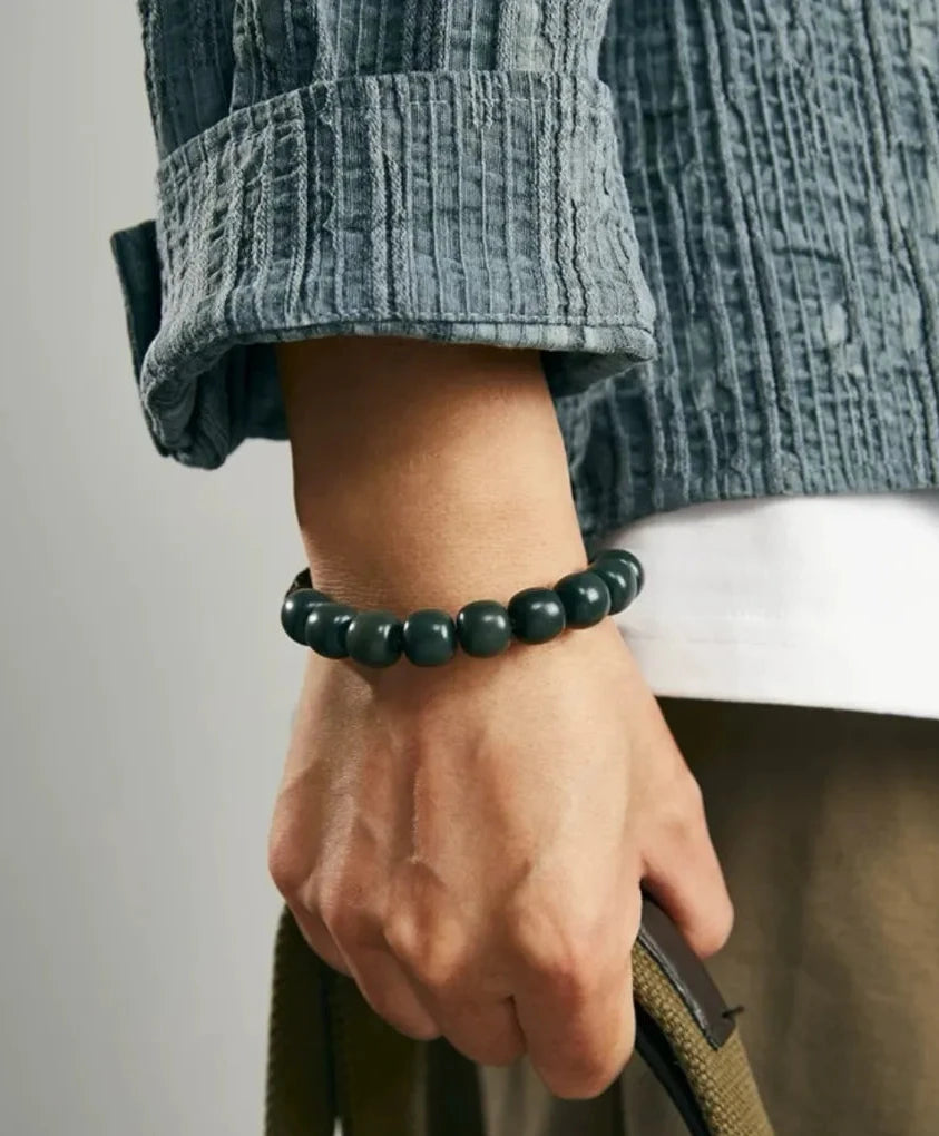 Side profile on wrist, capturing the dangling silver skull charms and the rugged texture of the cotton cord
