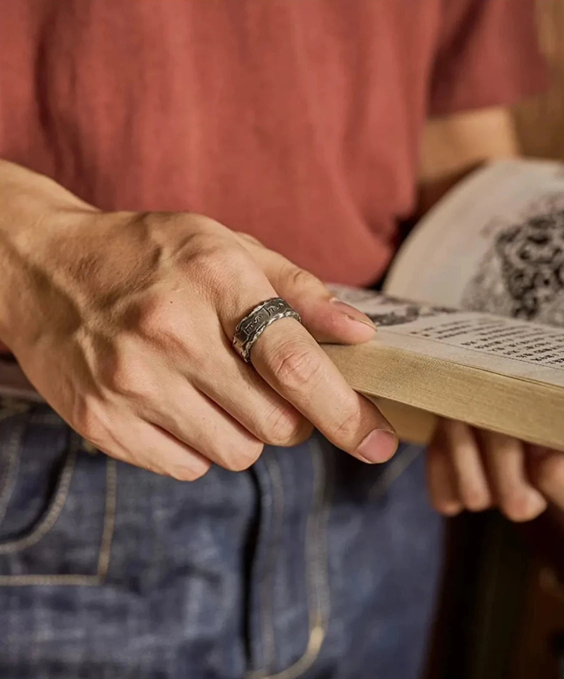 Close-up of the Shift Ring worn while reading a book, emphasizing the spiritual and mindfulness aspect of the mantra design