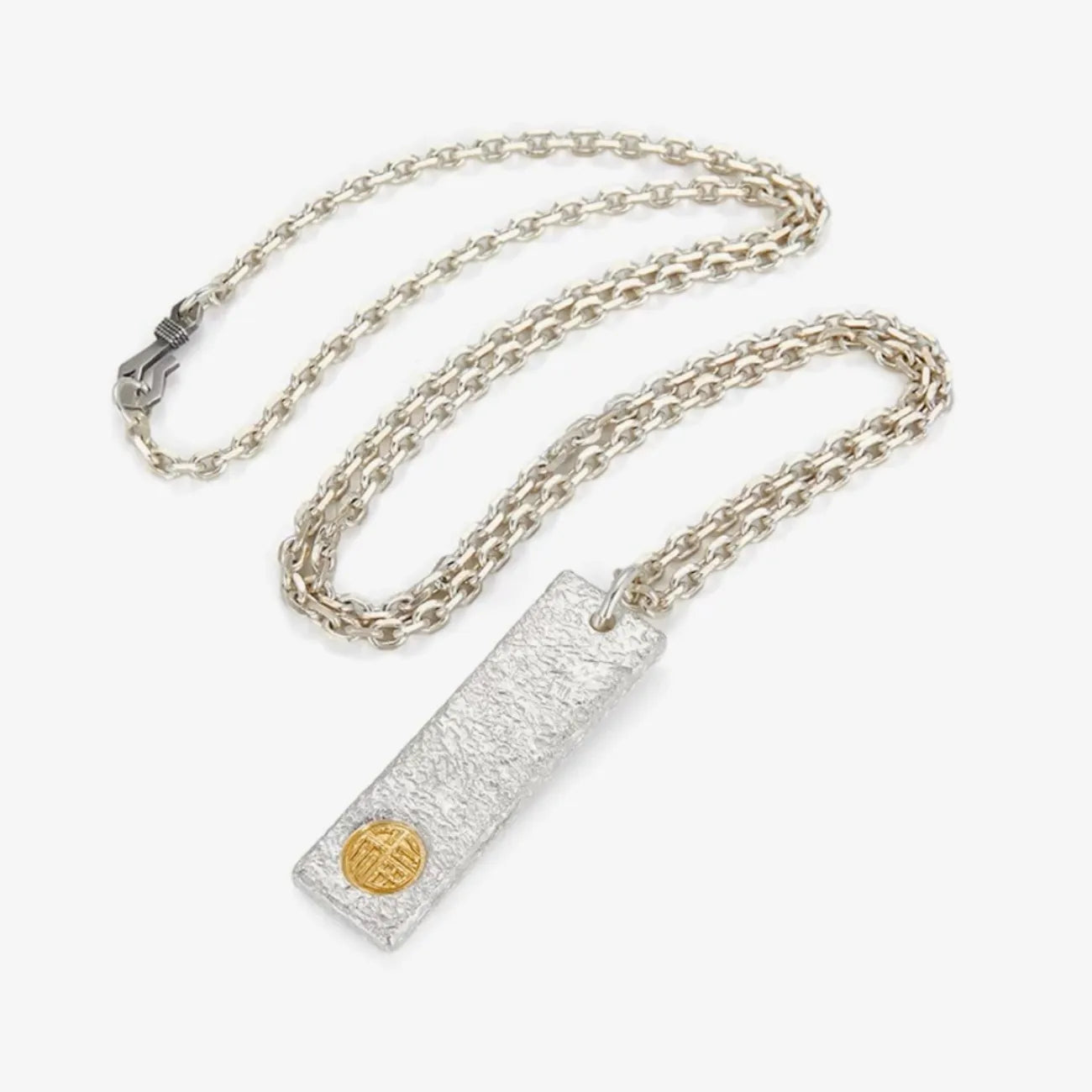 Flat lay of the Golden Bliss necklace featuring a textured silver bar with a gold symbol