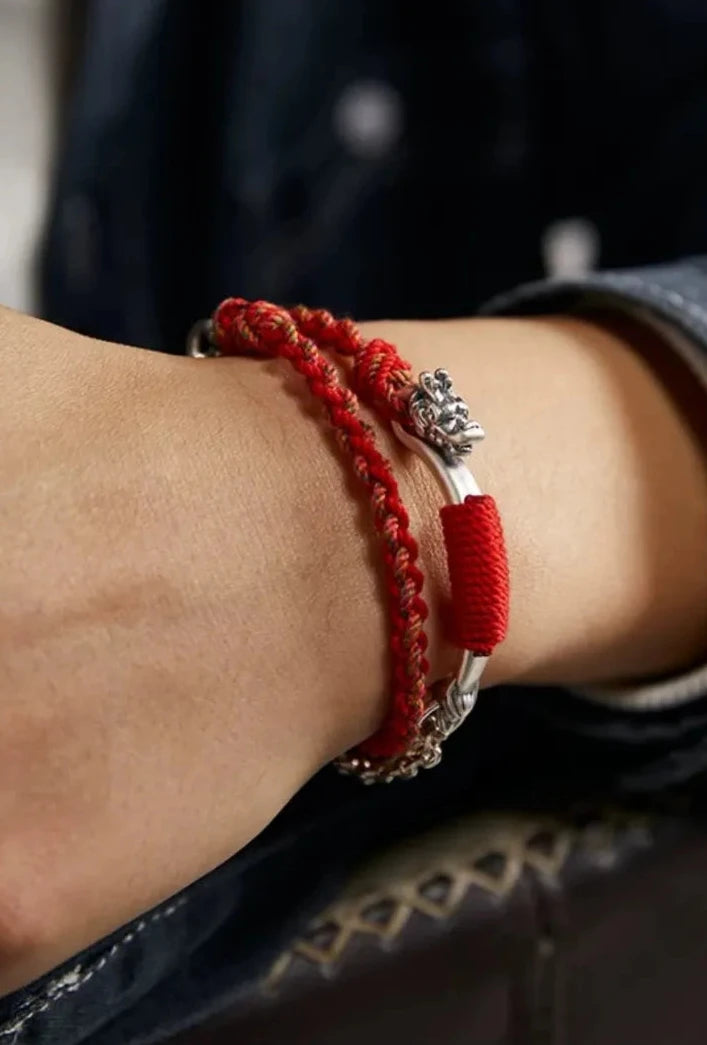 Close-up on wrist displaying the "mixed media" design: rugged silver chain paired with traditional red braided cord