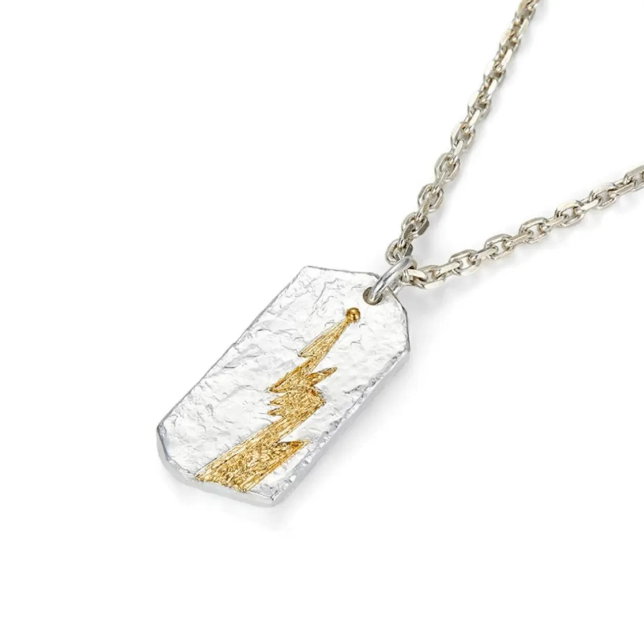 Angled shot of the silver lightning pendant showing the rugged texture and gold accent