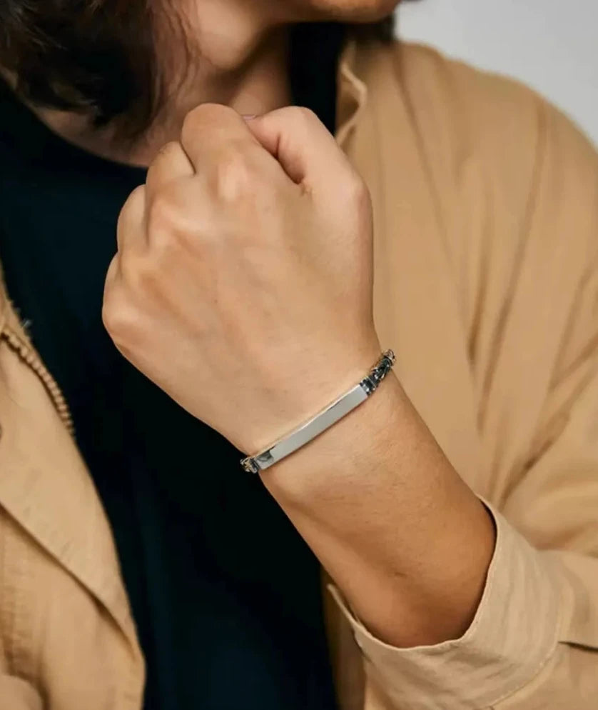 Lifestyle shot of a man in a beige overshirt wearing the sleek ID bracelet, showing its low profile on the wrist