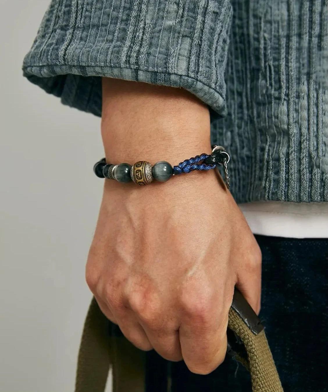 Close-up of the back of the wrist, demonstrating the adjustable sliding knot mechanism and the dangling silver charm