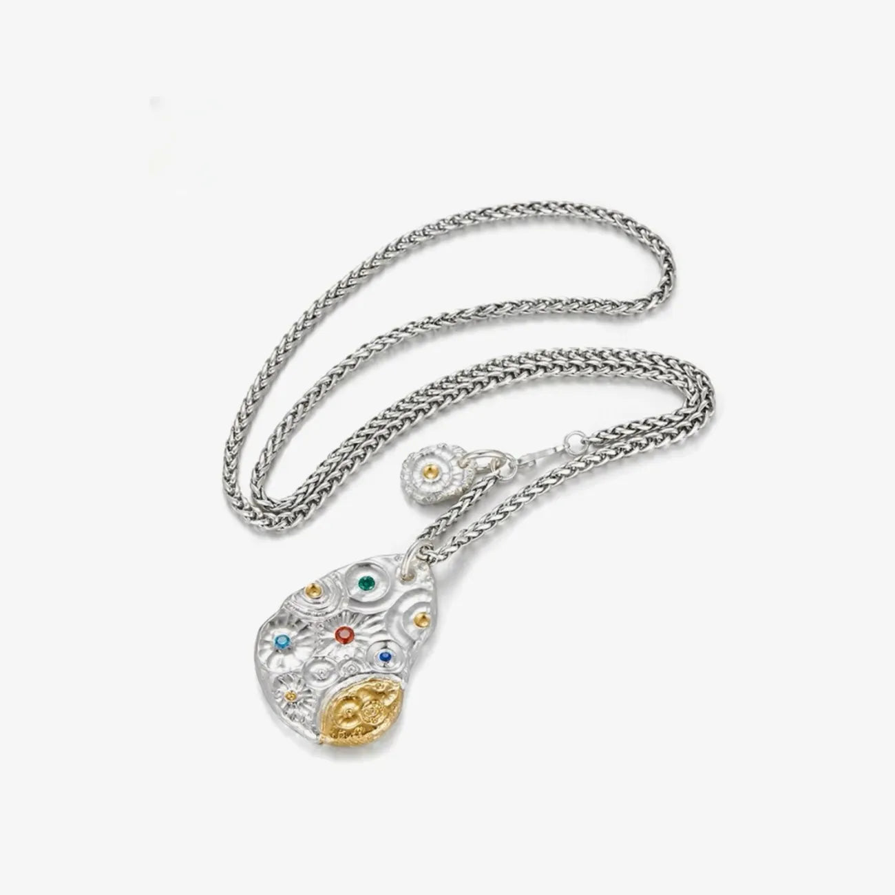 Flat lay of the Starway necklace with a thick silver chain and gemstone-encrusted pendant