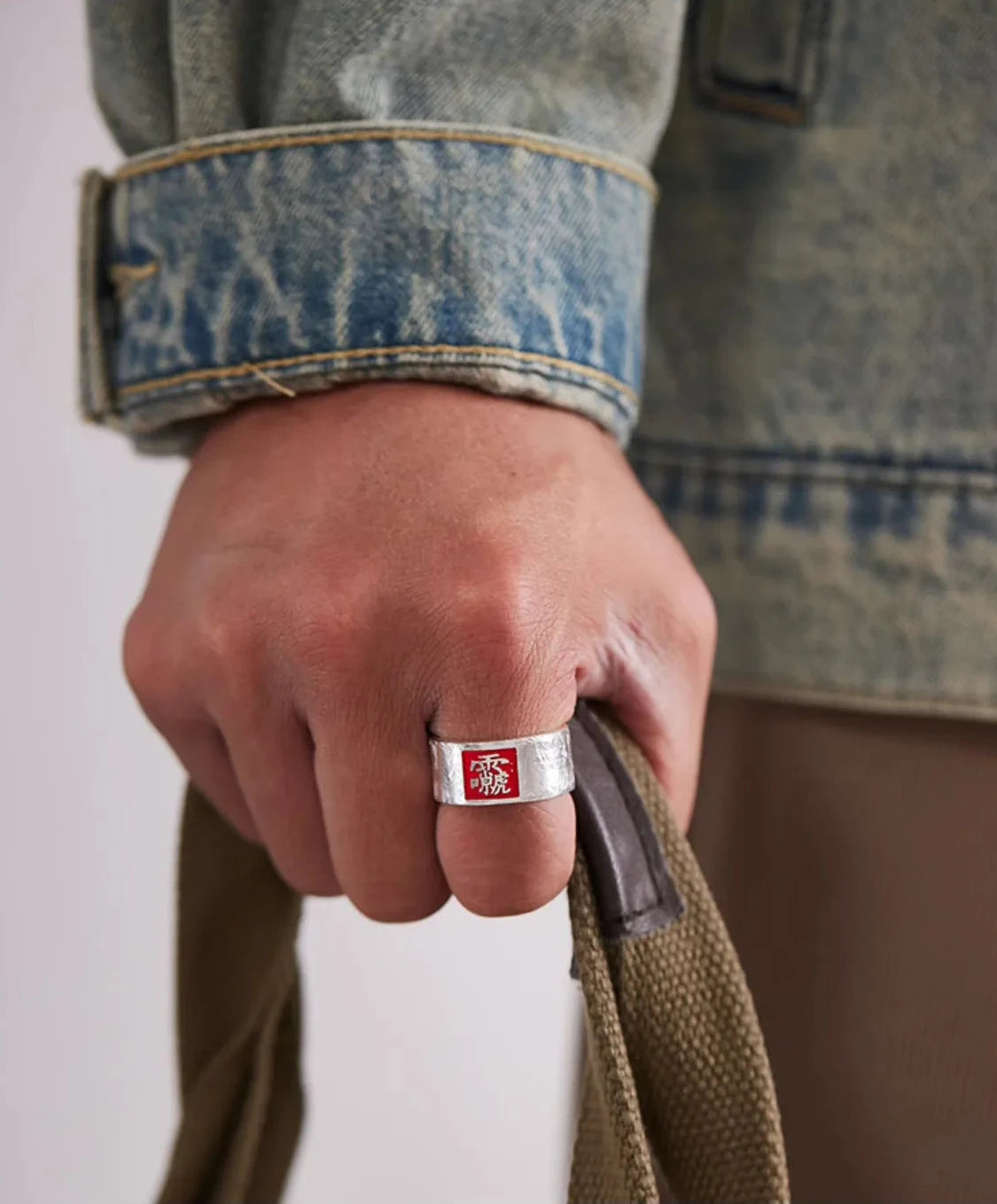 Model displaying the side details of the silver amulet ring, highlighting the red flame motifs in a casual pose