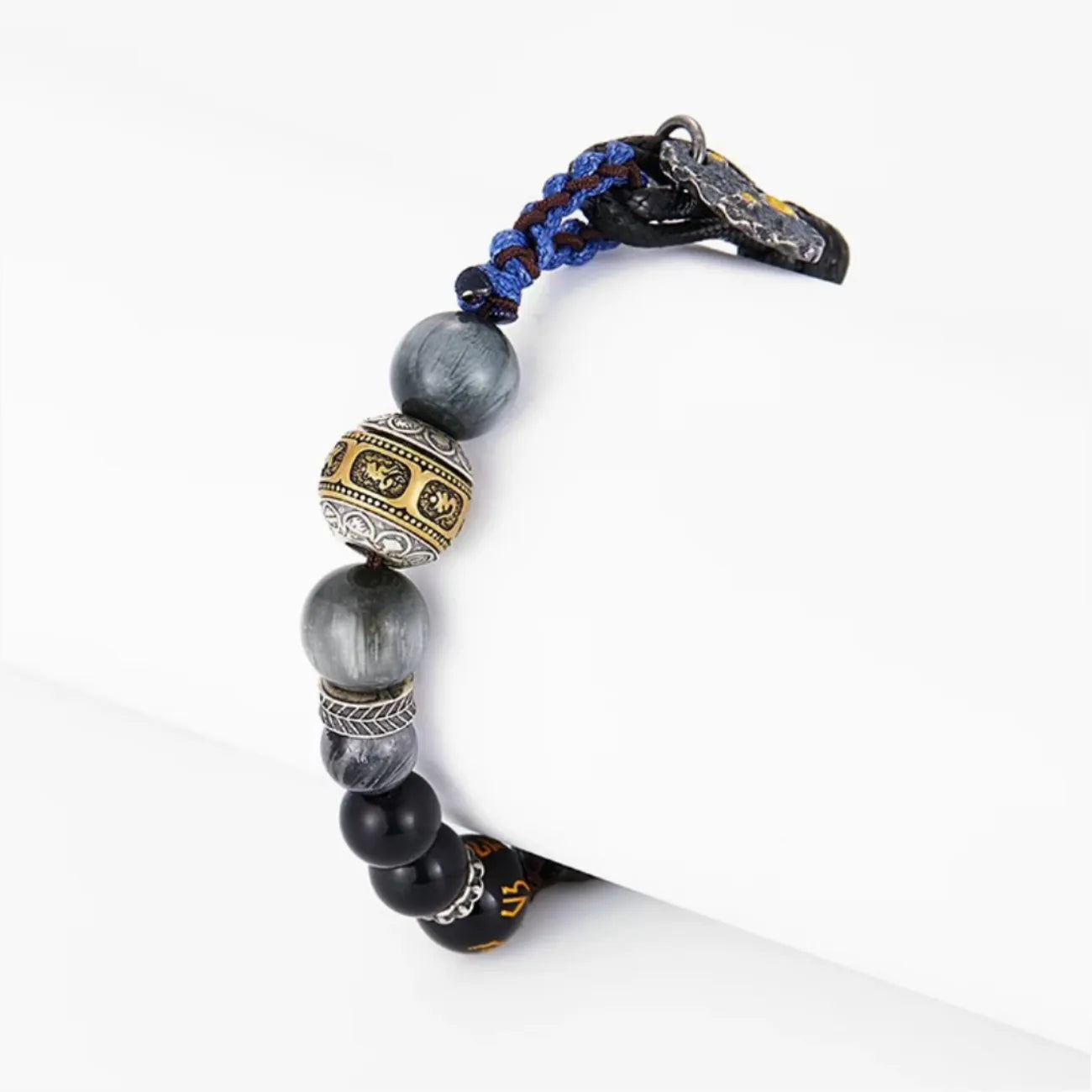 Side profile showing the intricate details of the central Tibetan mantra bead and the chatoyant grey gemstone texture