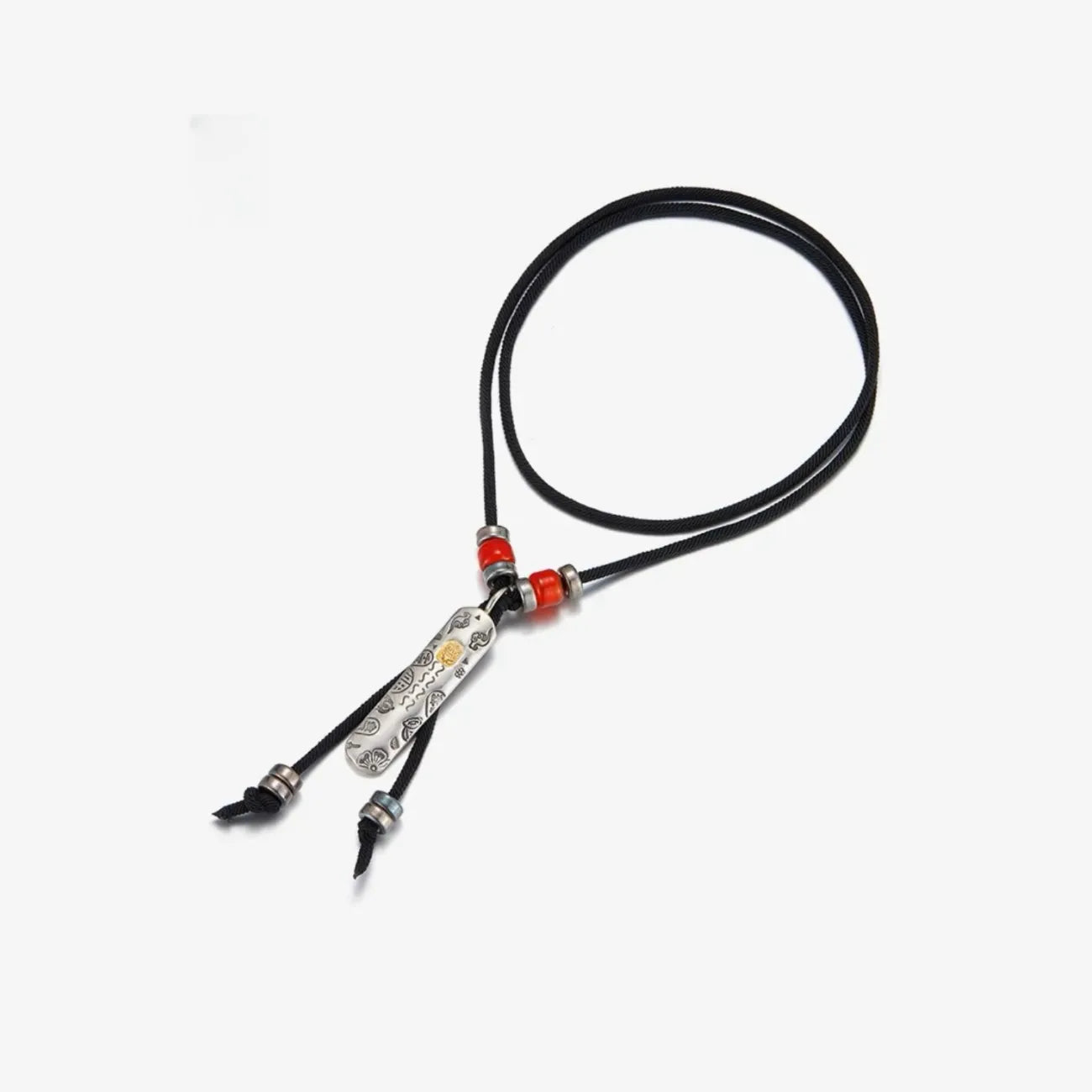 Flat lay of the necklace showing the black braided cord, vermilion red beads, and the full length of the silver charm