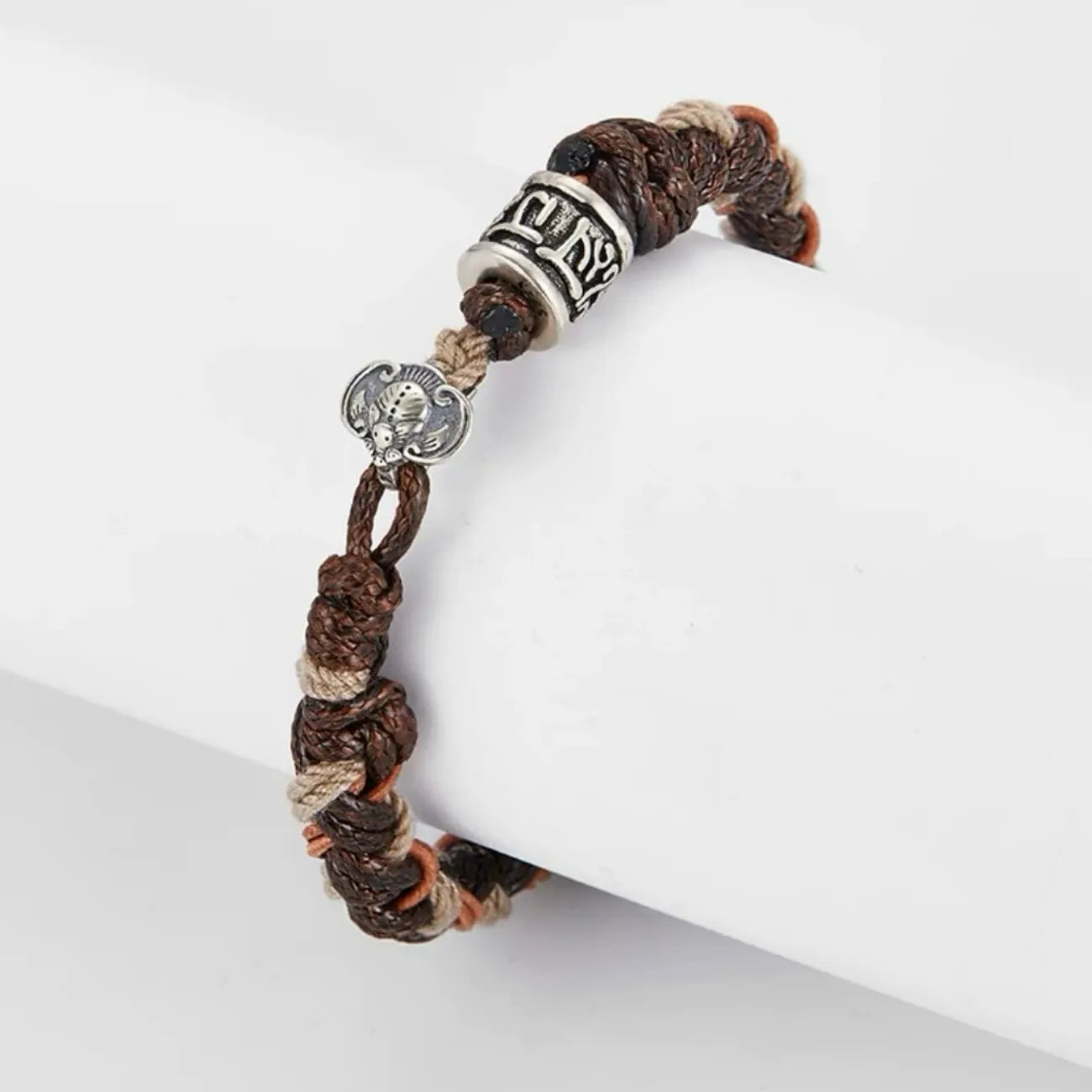 Side profile showing the intricate braiding of brown waxed cotton, khaki thread, and orange leather strips