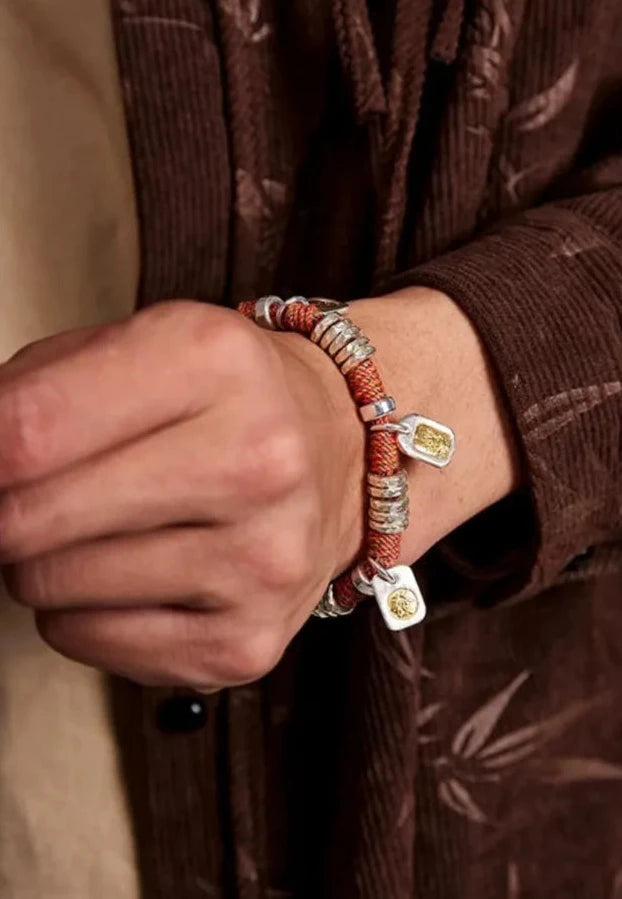 Close-up on the wrist showing the central tiger face charm and the ancient coin tag, symbolizing power and prosperity