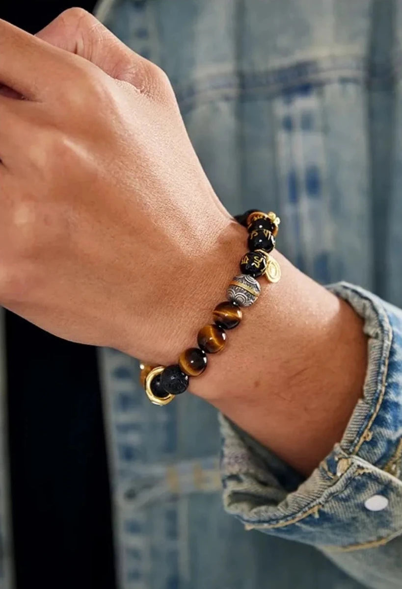 Close-up on the wrist against a denim jacket, showcasing the chatoyancy of the tiger eye and the clarity of the yellow stones