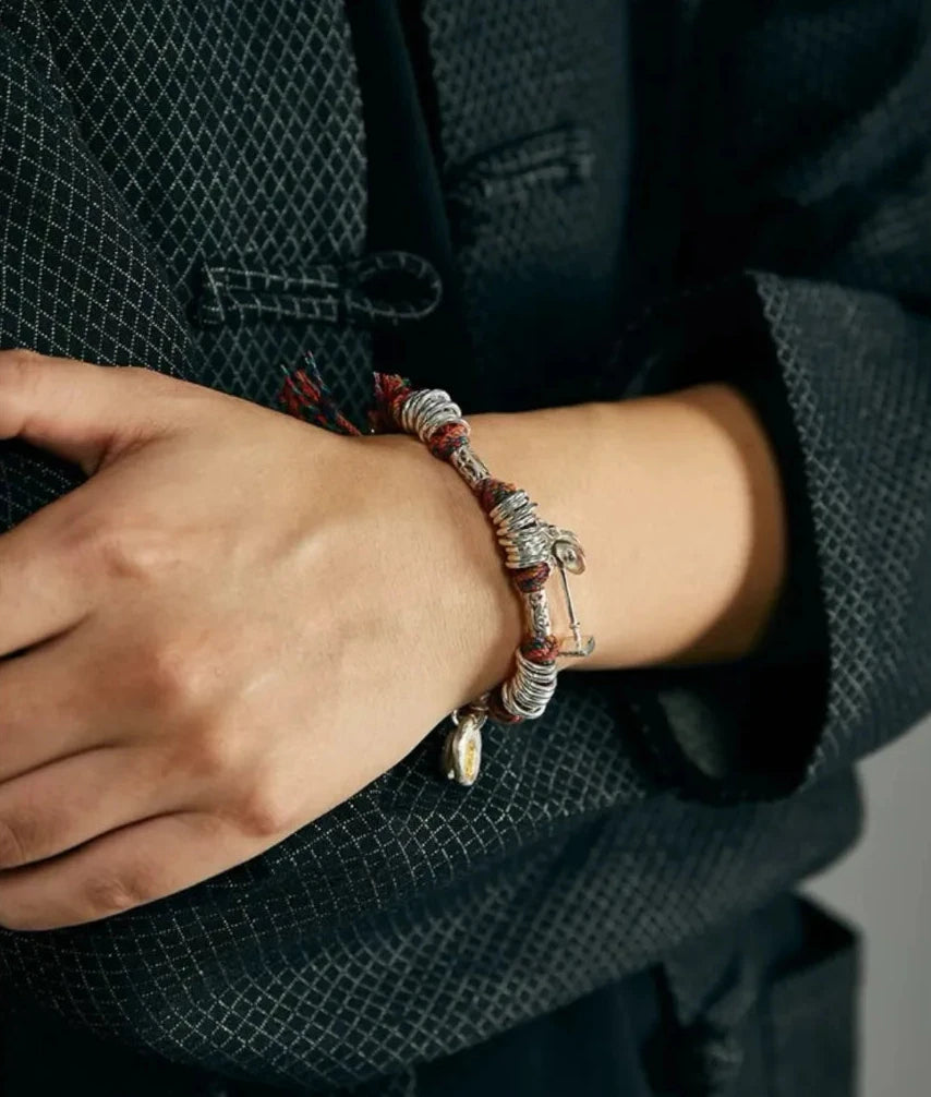 Close-up on the wrist featuring the dangling silver shovel charm, symbolizing ambition and hard work