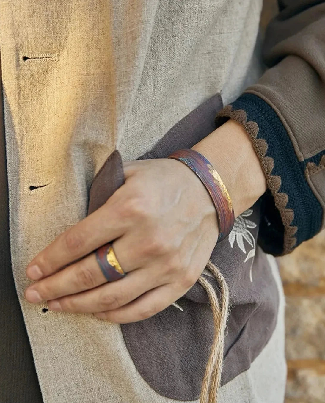 Close-up of the bangle on the wrist, showcasing how the gold accent catches the light against the matte oxidized background