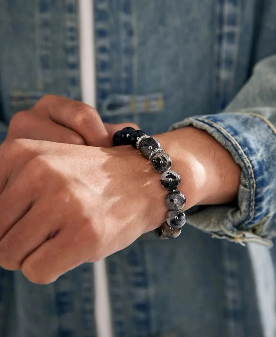 Lifestyle shot of a man in a denim jacket wearing the Vanquisher bracelet, showcasing its perfect match with casual streetwear