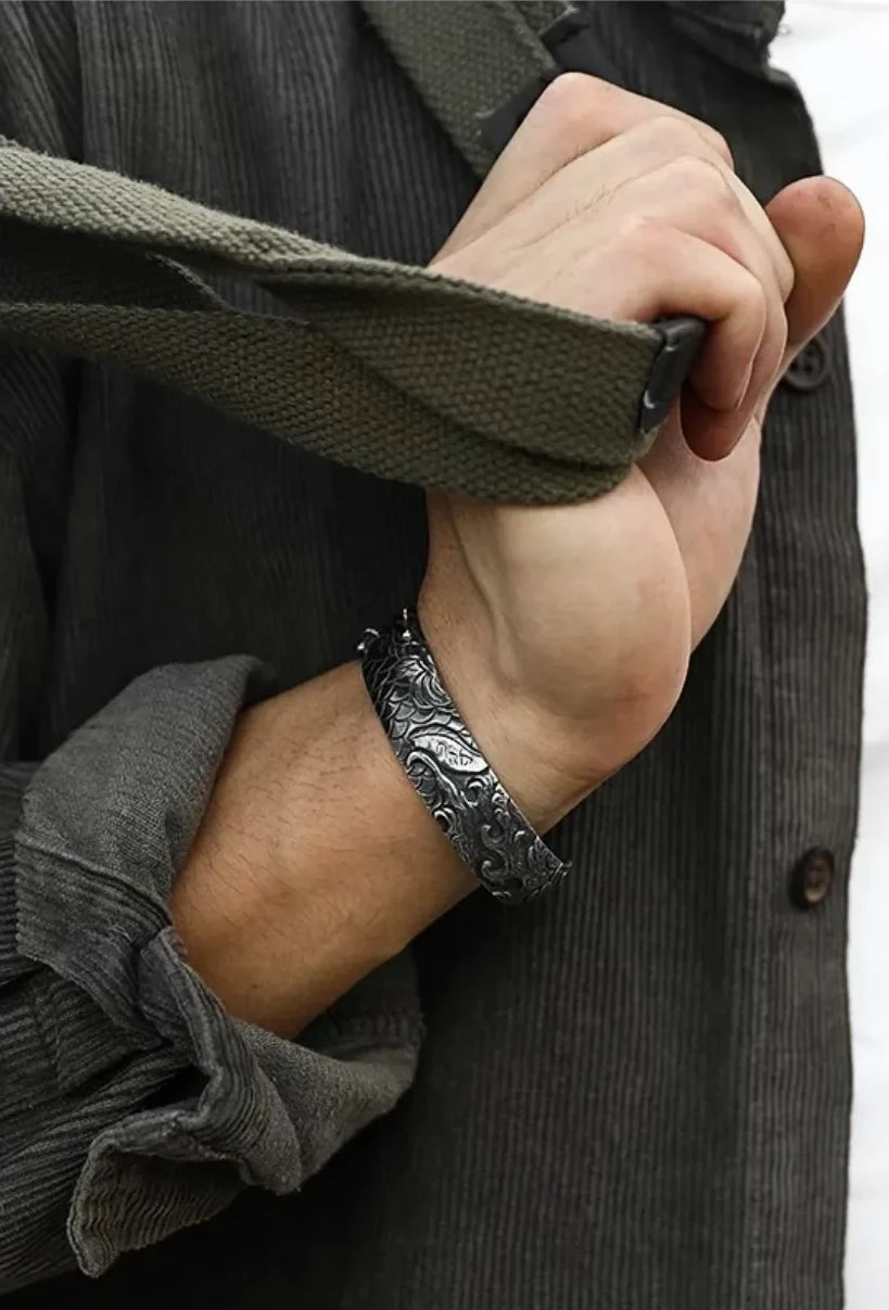 Model wearing a grey corduroy shirt holding a bag strap, with the mixed-metal carp bangle adding a touch of vintage luxury