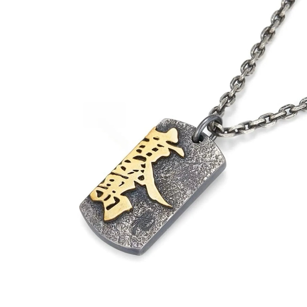 Angled shot of the vintage-style silver pendant showing the raised gold calligraphy and distressed texture