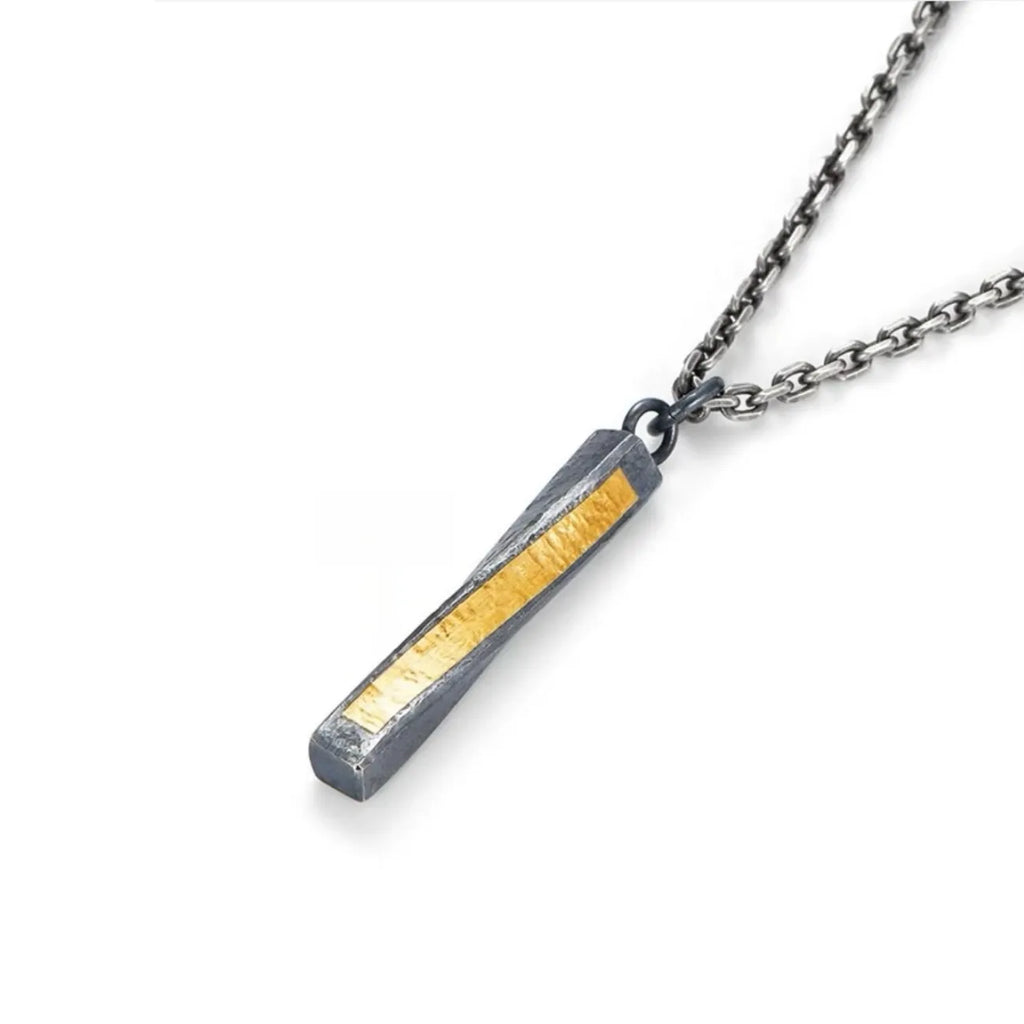 Close-up detail of the pendant's side profile, highlighting the contrast between the dark silver and bright gold accent