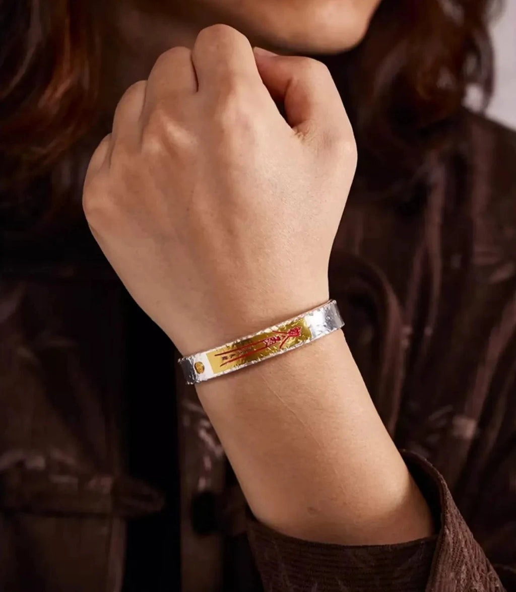 A fist pose demonstrating the bold presence of the bangle, highlighting the gold stamp and the unique hammered texture