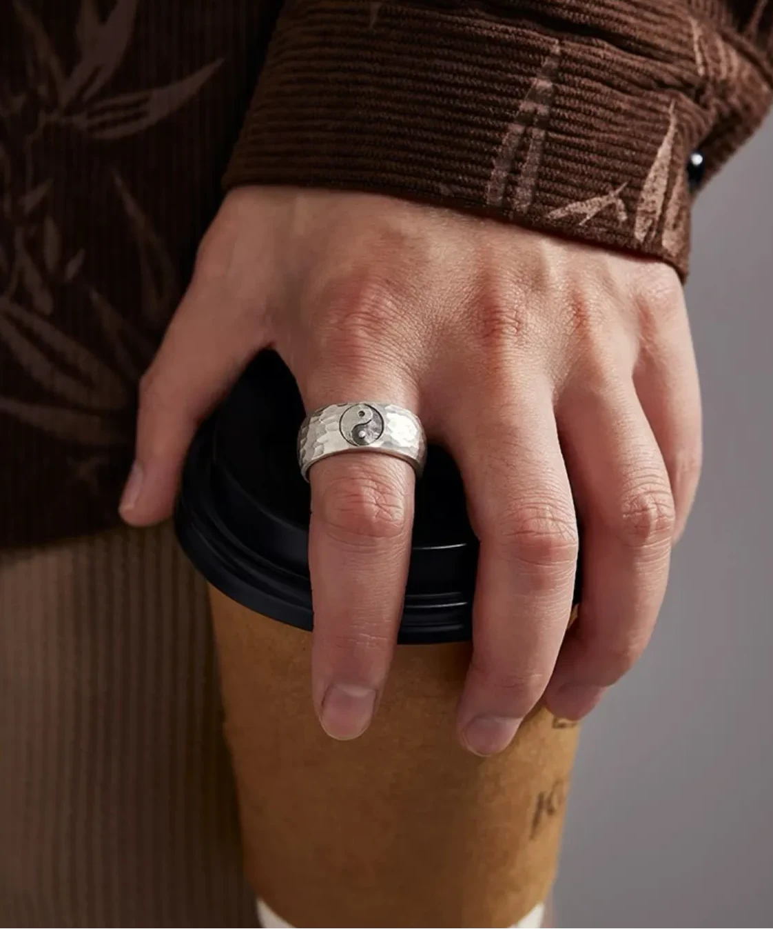 Close-up of the ring's hammered texture catching the light, worn as a daily reminder of balance and mindfulness during a coffee break