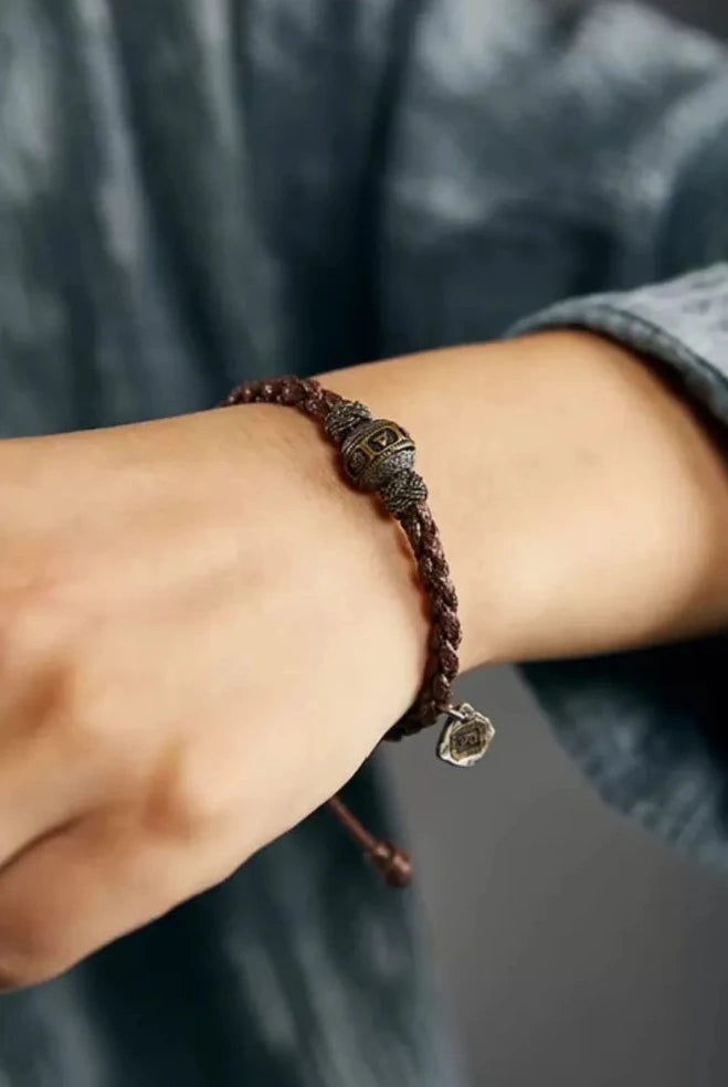 Close-up on the wrist showing the rich texture of the brown waxed cord against blue linen fabric